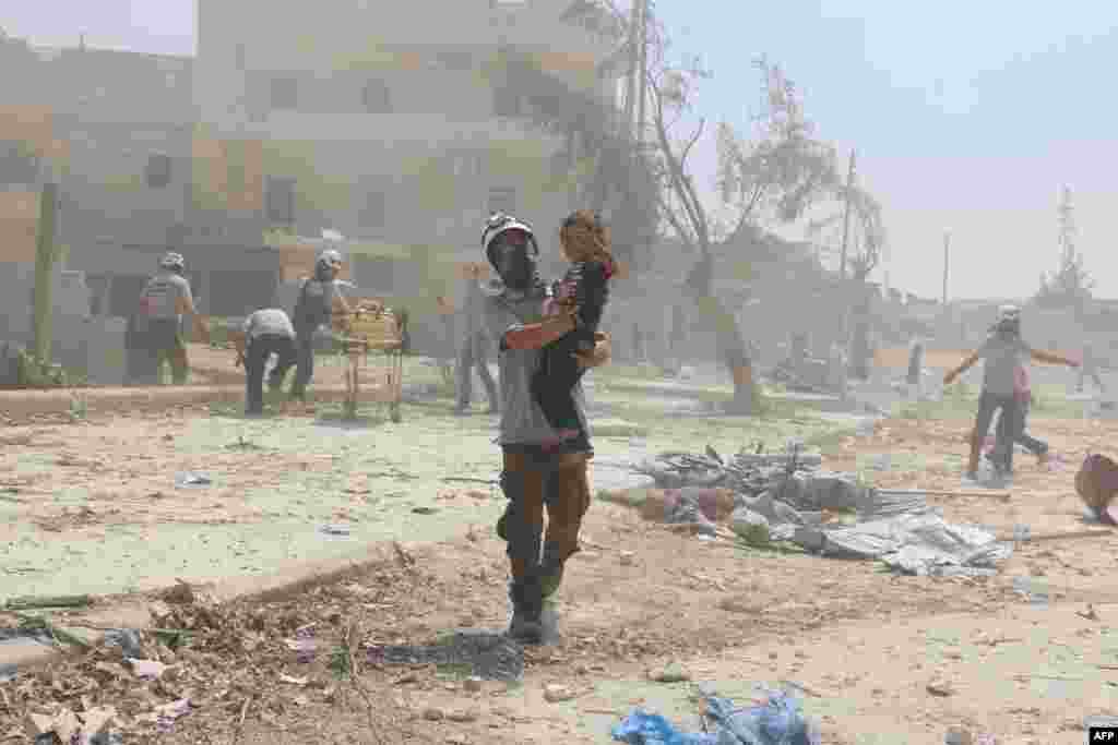 Seorang petugas penyelamatan Suriah menggendong seorang anak di distrik Maadi, Aleppo (27/8).&nbsp;(AFP/Ameer Alhalbi)