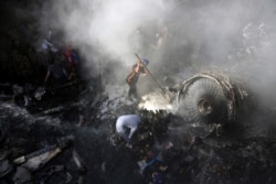 FILE - Volunteers look for survivors of a plane that crashed in a residential area of Karachi, Pakistan, May 22, 2020.