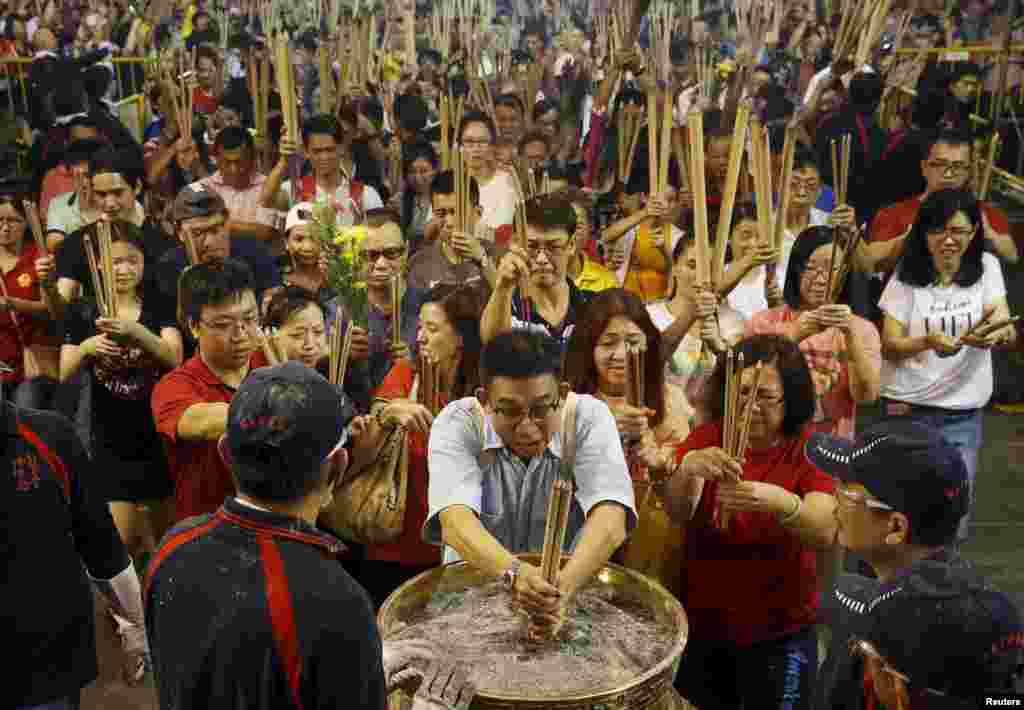 People rush to plant the first joss stick of the Lunar New Year of the Monkey at the stroke of midnight at the Kwan Im Thong Hood Cho temple in Singapore.
