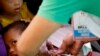 FILE - Philippine National Red Cross and Health Department volunteers conduct house-to-house measles vaccination to children at an informal settlers community in Manila, Feb. 16, 2019.