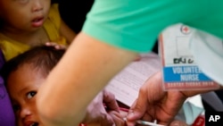 FILE - Philippine National Red Cross and Health Department volunteers conduct house-to-house measles vaccination to children at an informal settlers community in Manila, Feb. 16, 2019.