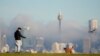FILE - A man gestures to his dog as fog drifts through the buildings in Sydney's central business district, Australia, June 11, 2021.