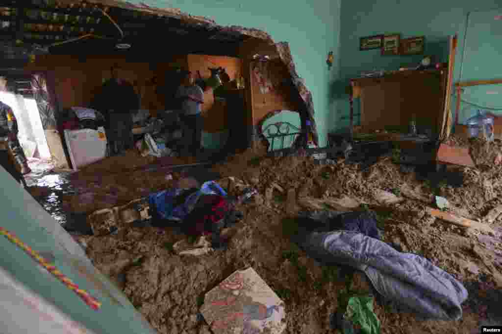 Warga berdiri di sebuah rumah yang terkena banjir lumpur menyusul longsor di sebuah gunung di Altotonga, negara bagian Veracruz (16/9). (Reuters/Oscar Martinez)