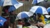 Rohingya refugees hide under umprellas during rainfall at Kutupalong refugee camp in Ukhia, Cox's Bazar, Bangladesh, Sept. 12, 2019. 