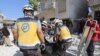 Members of the Syrian Civil Defense carry away a body retrieved from the rubble following a reported regime airstrike on the village of Kafriya, in Syria's Idlib province, July 13, 2019.