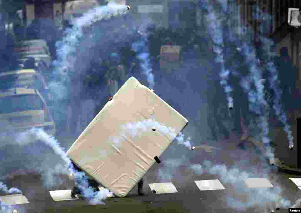 Youths take cover from tear gas grenades behind a mattress during clashes as French high school and university students attend a demonstration against the labor law proposal in Nantes, France, as part of nationwide labor reform protests and strikes.