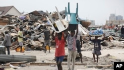 Des enfants transportent des chaises en plastique récupérées des maisons démolies et incendiées par des fonctionnaires du gouvernement à Lekki, Lagos, au Nigeria, 12 novembre 2016