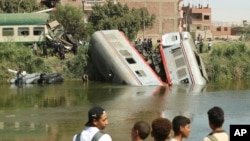 People stand by the wreckage after a locomotive crashed into the tail of the Cairo-bound passenger train in southern Egypt, in the province of Minya, about 168 miles south of Cairo, Oct. 13, 2024. 
