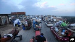 Truckloads of civilians flee a Syrian military offensive in Idlib province on the main road near Hazano, Syria, Dec. 24, 2019. Syrian forces launched a wide ground offensive last week into the northwestern province of Idlib.