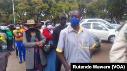 Zinbabweans wait in a long line to be vaccinated