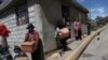 Residents wearing protective face masks hold food boxes distributed by the government during a lockdown to contain the spread of COVID-19, on the outskirts of Quito, Ecuador, May 27, 2020.