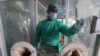An employee cleans a booth at a testing and screening facility for the new coronavirus, in a hospital in Karachi, Pakistan, Friday, July 17, 2020. (AP Photo/Fareed Khan)