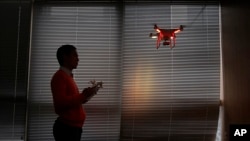 FILE - A staff member from DJI Technology Co. demonstrates the remote flying with a drone inside his office in Shenzhen, south China's Guangdong province, on Dec. 15, 2014. China imposed restrictions July 31, 2023 on exports of long-range civilian drones.