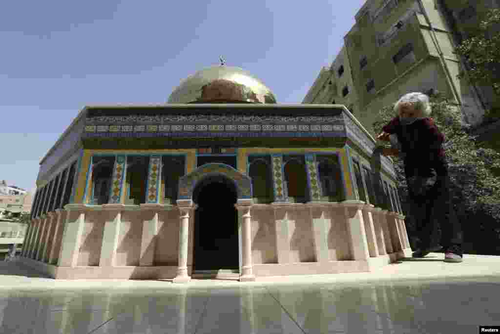 Seniman Yordania Nezam Nimeh membersihkan karyanya, yang merupakan tiruan dari &#39;Dome of the Rock&#39; atau Kubah Shakhrah di Amman, Yordania.