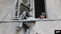 Žena gleda kroz prozor zgrade koja je oštećena tokom izraelskog bombardovanja u naselju Al-Daraj u gradu Gaza 21. maja 2024. godine (Fotografija AFP)