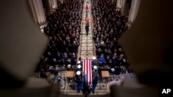 The flag-draped casket of former President George H.W. Bush is carried by a military honor guard during a State Funeral at the National Cathedral, Dec. 5, 2018, in Washington. 