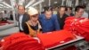 FILE PHOTO - Prime Minister Hun Sen, center, leans over a garment worker during a visit to a factory outside of Phnom Penh, Cambodia, Wednesday, Aug. 30, 2017. The country's garment and footwear sectors have been critical to its economic growth.