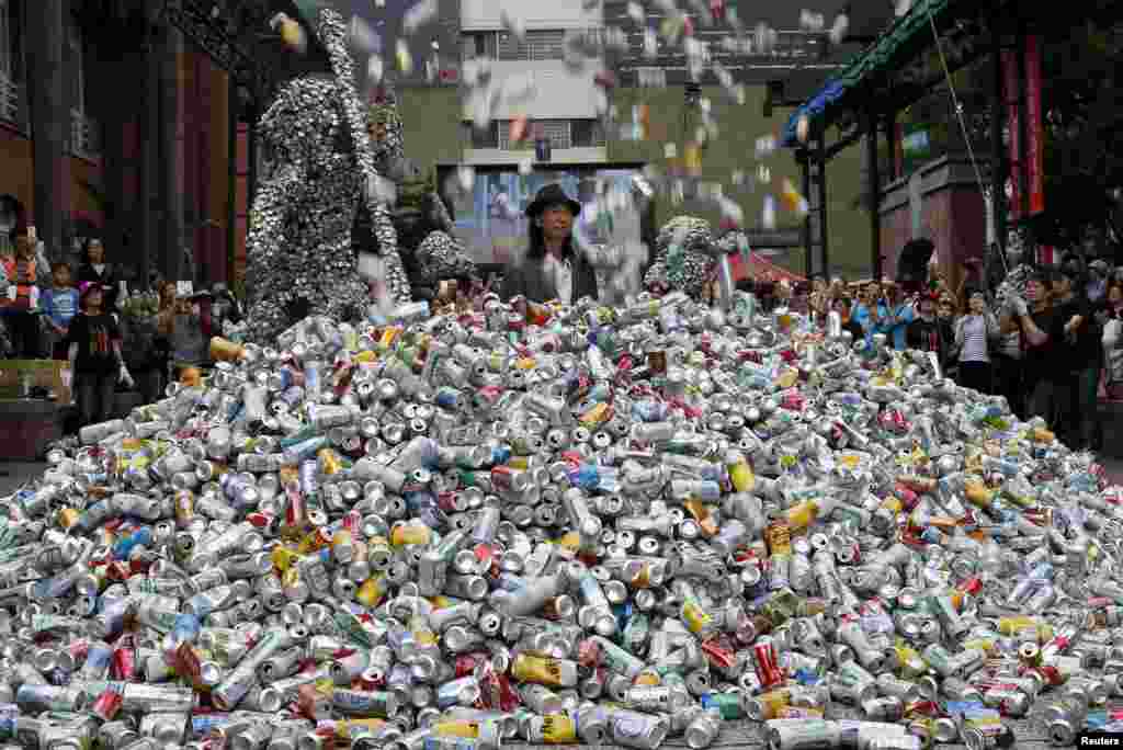 Artist Chin Chih Yang performs "Kill Me or Change" with 30,000 cans falling and burying the artist underneath a mountain of garbage, at the Museum of Contemporary Art in Taipei, Taiwan, April 23, 2016.