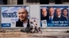 FILE - People walk by election campaign billboards showing Israeli Prime Minister Benjamin Netanyahu, left, alongside the Blue and White party leaders, from left to right, Moshe Yaalon, Benny Gantz, Yair Lapid and Gabi Ashkenazi, in Tel Aviv, Israel, April 3, 2019.