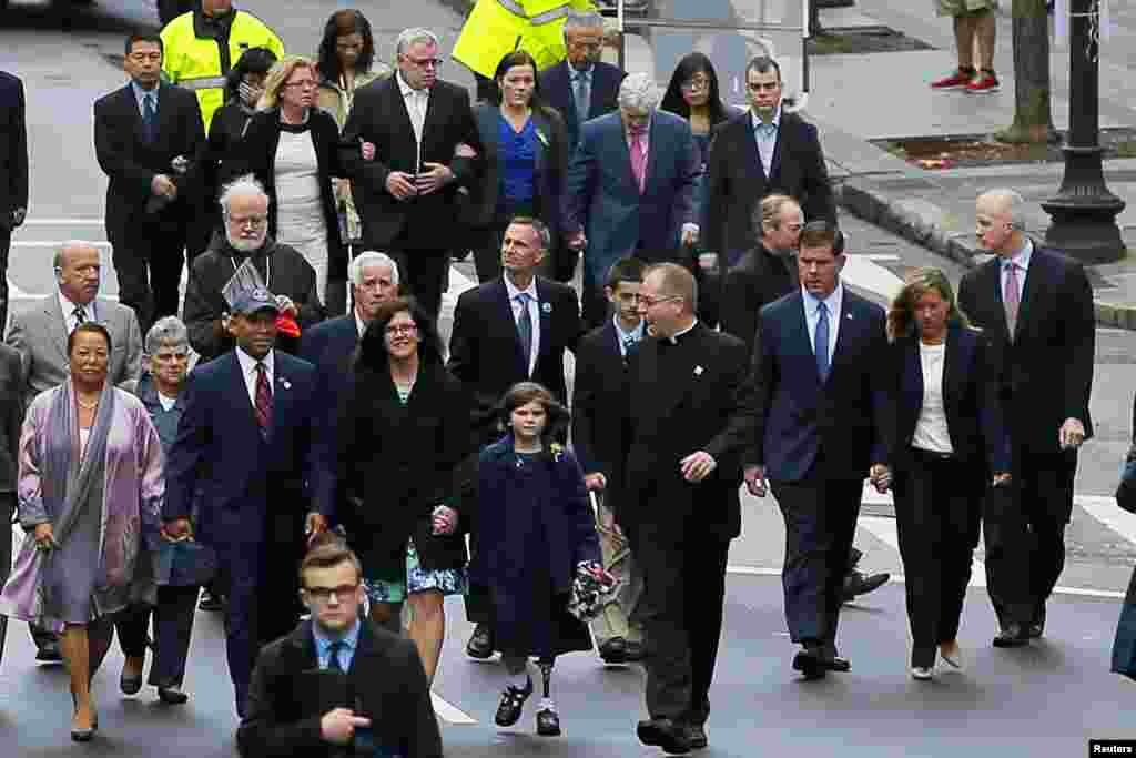 Para anggota keluarga korban pemboman Maraton Boston 2013 bersama Gubernur Massachusetts Deval Patrick (mengenakan topi bisbol, kiri) dan Walikota Boston Marty Walsh (ketiga dari kanan) saat berjalan menuju garis finish (15/4). (Reuters/Brian Snyder)
