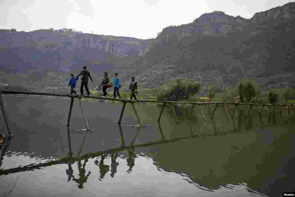 Warga berjalan melewati sebuah jembatan sebelum mereka bekerja di pabrik teh di kota Xinchang, provinsi Zhejiang, China (30 Maret 2013). 