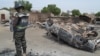 FILE - A Nigerian policeman stands guard by burned out cars and houses, following an attack by suspected Islamic extremists in Kawuri, Maiduguri, Nigeria.