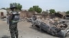 FILE - A Nigerian policeman stands guard by burned out cars and houses, following an attack by suspected Islamic extremists in Kawuri, Maiduguri, Nigeria.