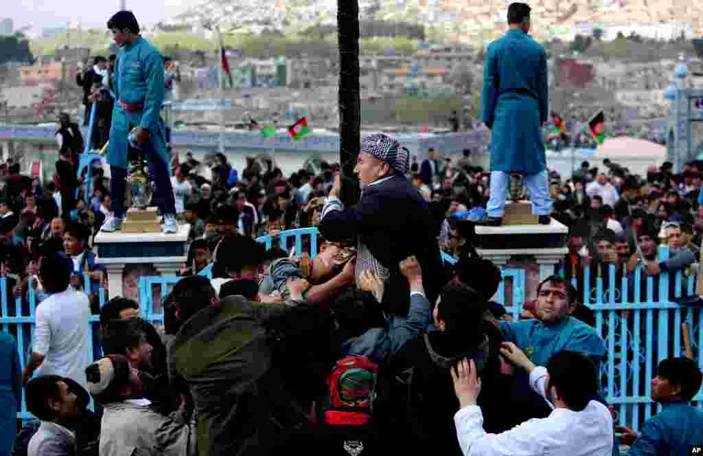 Afghan Shi&#39;ite men kiss the holy mace for blessings during Nowruz celebrations, at the Kart-e-Sakhi Shrine in Kabul.