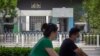 People wearing face masks to protect against the new coronavirus ride past the Australian Embassy in Beijing, June 6, 2020. 