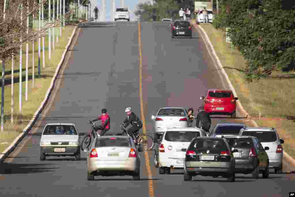 Brazil's President Dilma Rousseff is surrounded by cars as she rides her bicycle followed by security guards near Alvorada Palace, the presidential residence, in Brasilia.