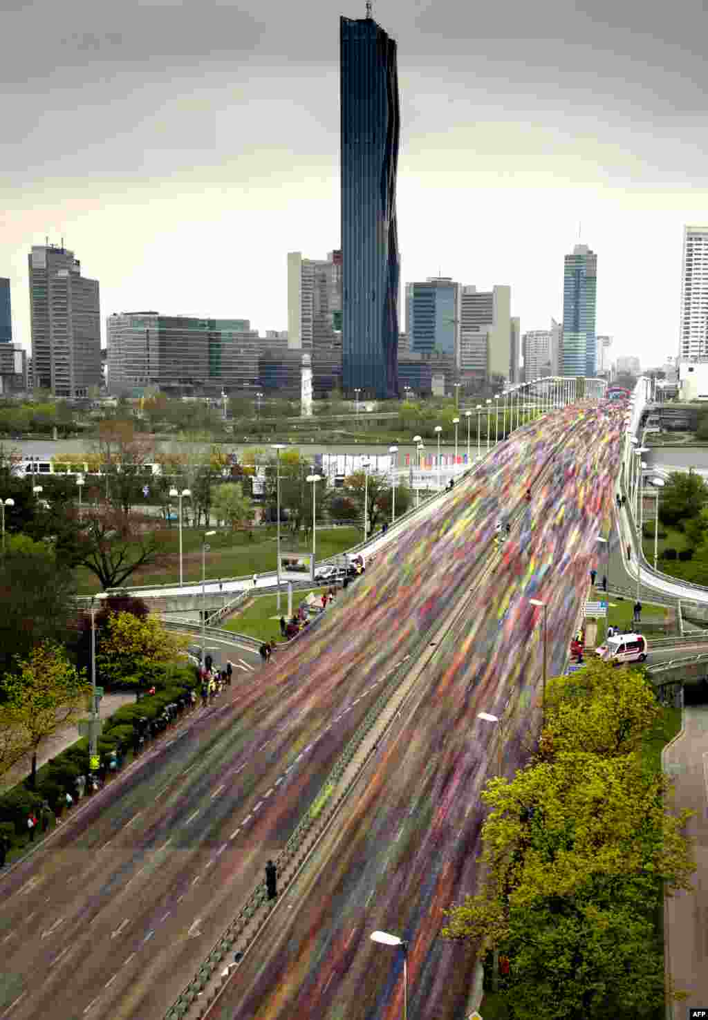 Thousands of runners are seen during a long exposure crossing the Reichsbrucke bridge over the Danube river, during the Vienna City Marathon, Austria.